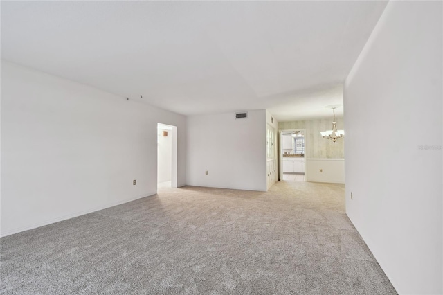 carpeted empty room featuring an inviting chandelier