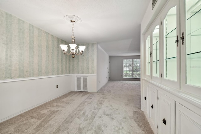 empty room featuring a chandelier and light carpet