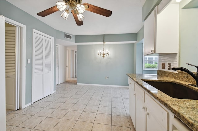 kitchen featuring ceiling fan with notable chandelier, pendant lighting, white cabinets, sink, and light tile patterned flooring