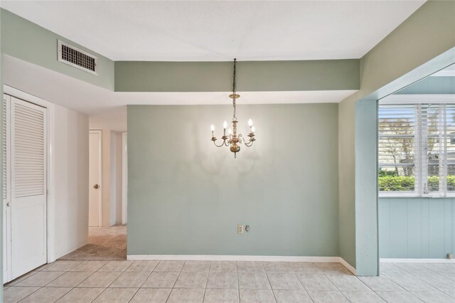 spare room with light tile patterned floors and a chandelier