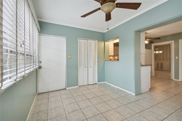 tiled empty room featuring ceiling fan with notable chandelier and crown molding