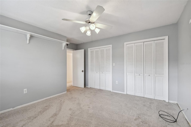 unfurnished bedroom with light carpet, multiple closets, and ceiling fan