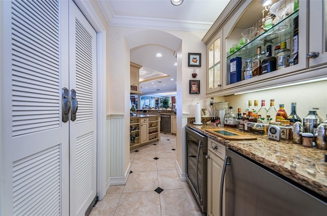 bar with dark stone counters, crown molding, dishwasher, light tile flooring, and a tray ceiling