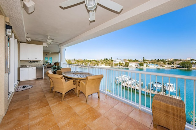 balcony with area for grilling, a water view, and ceiling fan