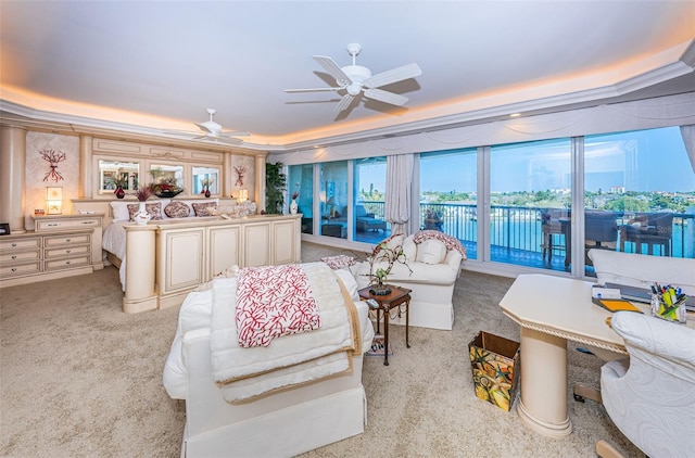 carpeted living room with ceiling fan and a tray ceiling