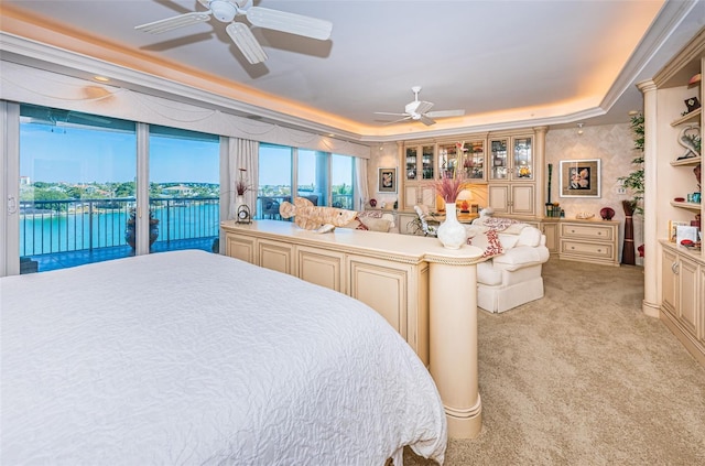 carpeted bedroom featuring access to outside, a tray ceiling, ceiling fan, and a water view