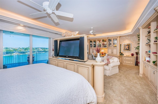 carpeted bedroom with access to outside, a tray ceiling, ceiling fan, and a water view