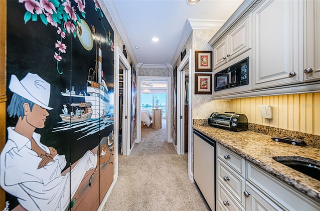 kitchen featuring light stone countertops, black microwave, white cabinets, ornamental molding, and light carpet