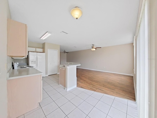 kitchen featuring range, white refrigerator with ice dispenser, ceiling fan, light tile flooring, and light brown cabinetry