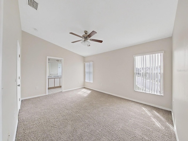 carpeted empty room with ceiling fan, lofted ceiling, and a healthy amount of sunlight