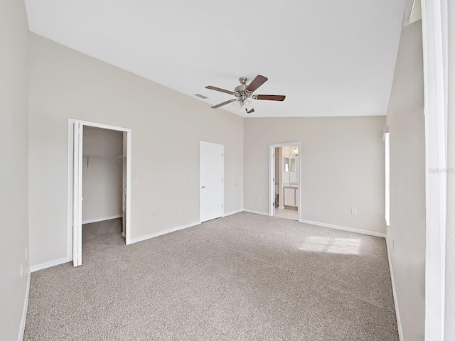 unfurnished bedroom featuring light carpet, lofted ceiling, a spacious closet, and ceiling fan