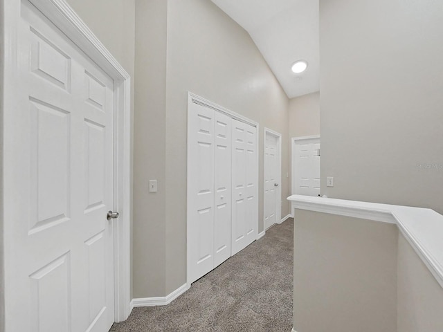 hall with vaulted ceiling and dark carpet