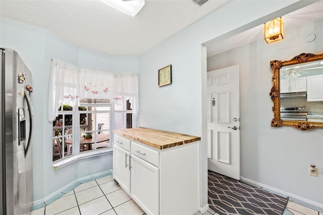 kitchen with appliances with stainless steel finishes, tasteful backsplash, ceiling fan, light tile floors, and white cabinets