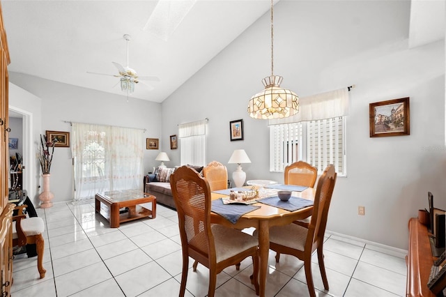 tiled dining area featuring high vaulted ceiling, ceiling fan with notable chandelier, a wealth of natural light, and a skylight