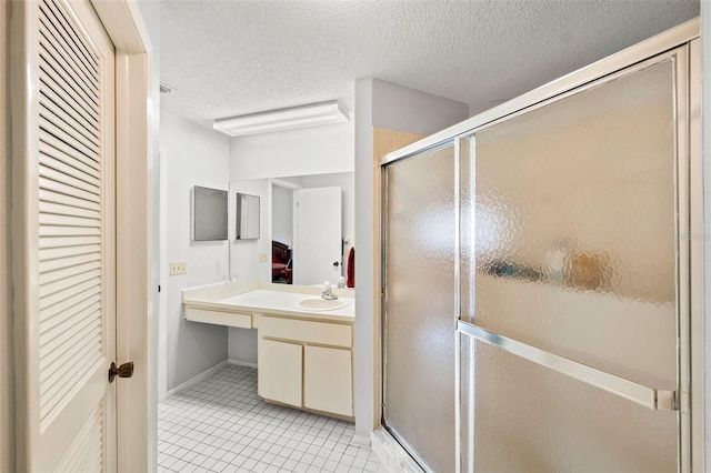 bathroom with a shower with door, tile floors, a textured ceiling, and vanity