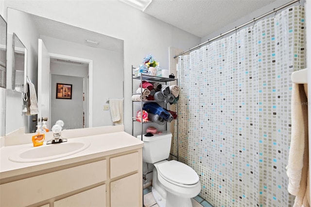 bathroom with toilet, a textured ceiling, tile flooring, and vanity with extensive cabinet space