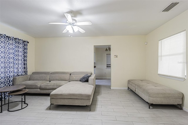 living area featuring baseboards, visible vents, and ceiling fan