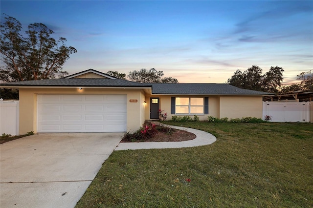 ranch-style house featuring a garage and a lawn