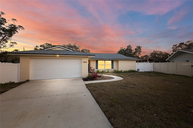 ranch-style home featuring a garage and a lawn