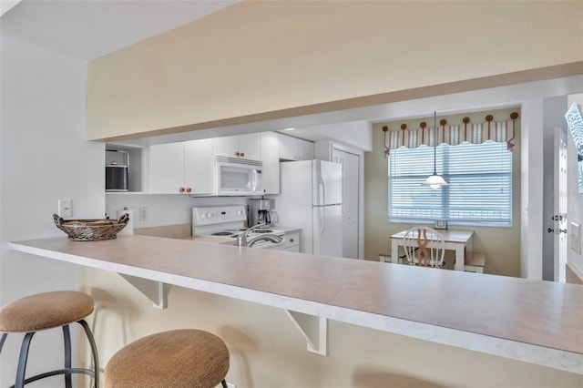 kitchen with a kitchen breakfast bar, white cabinets, pendant lighting, and white appliances