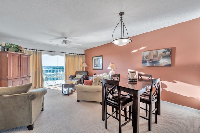 dining space featuring ceiling fan, light colored carpet, and a textured ceiling