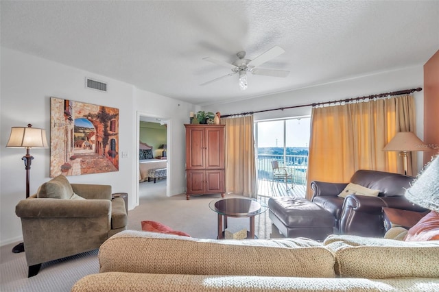 carpeted living room featuring ceiling fan and a textured ceiling