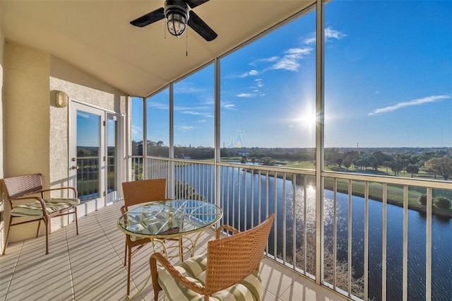 sunroom with ceiling fan and a water view