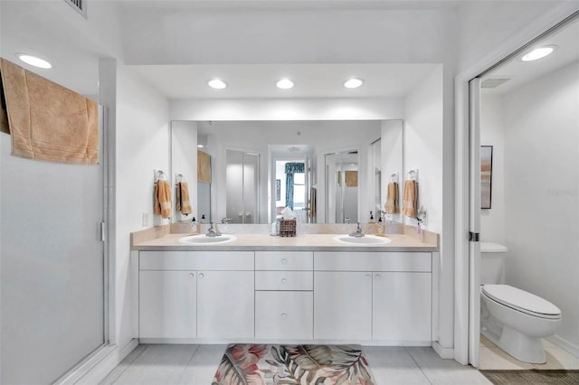 bathroom featuring tile patterned flooring, vanity, toilet, and a shower with shower door