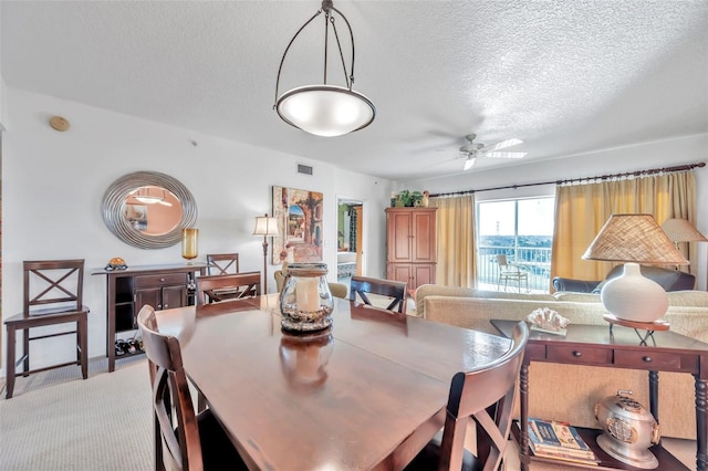 carpeted dining space featuring ceiling fan and a textured ceiling