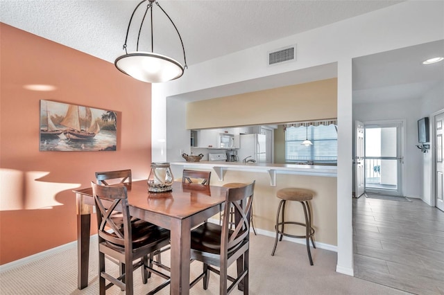 carpeted dining space featuring a textured ceiling