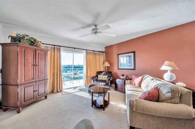 living room with ceiling fan, light colored carpet, and a textured ceiling