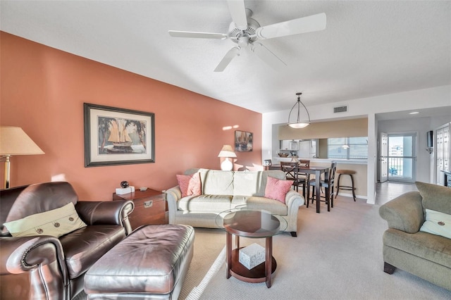 living room with light carpet, a textured ceiling, and ceiling fan