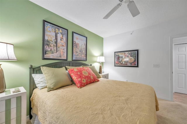 bedroom with ceiling fan, light colored carpet, and a textured ceiling