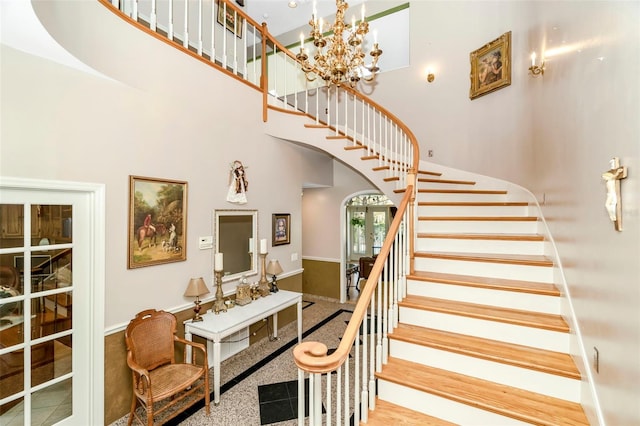 stairway featuring a high ceiling and a notable chandelier