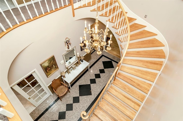 stairway with a chandelier and a towering ceiling