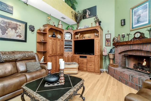 living room featuring light wood-type flooring and a brick fireplace