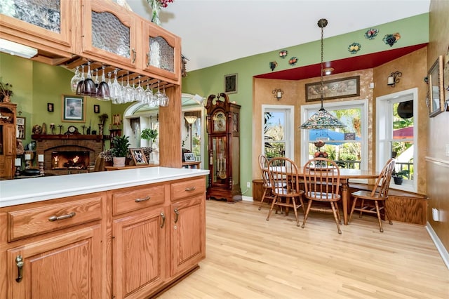 kitchen featuring pendant lighting, light wood-type flooring, and a brick fireplace