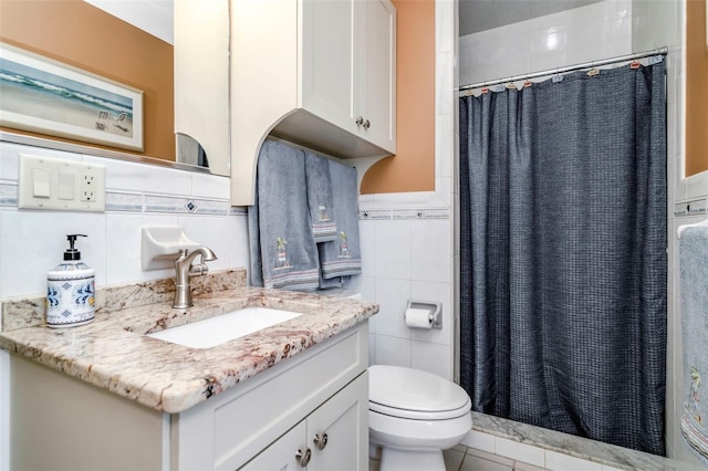 bathroom featuring vanity, a shower with curtain, tile patterned flooring, toilet, and tile walls