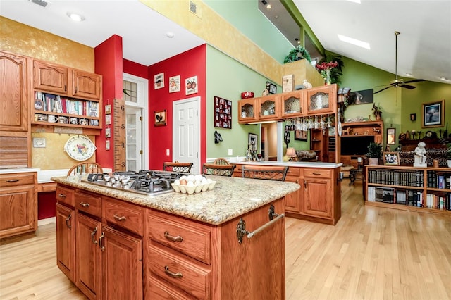 kitchen featuring a center island, light wood-type flooring, lofted ceiling, and stainless steel gas cooktop