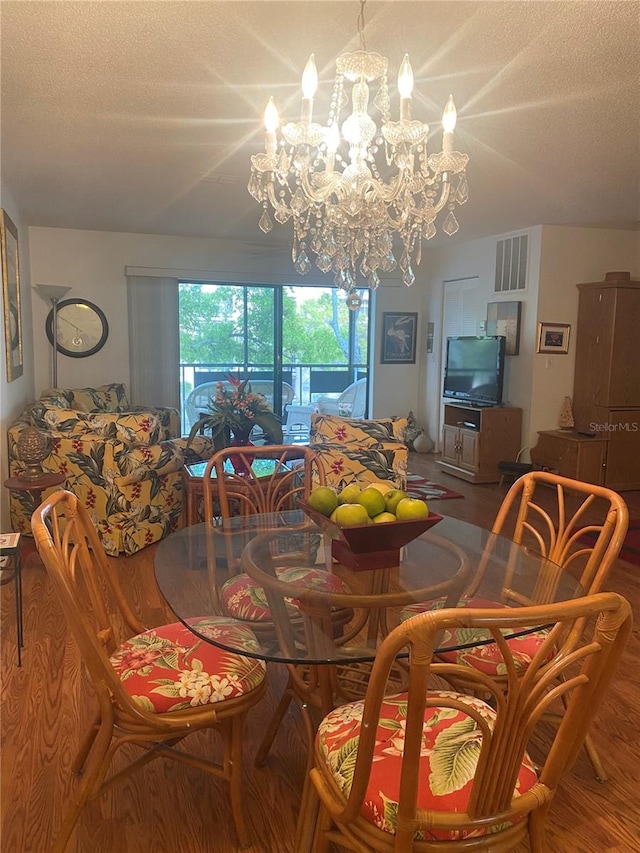 dining space featuring a textured ceiling, a chandelier, and hardwood / wood-style flooring