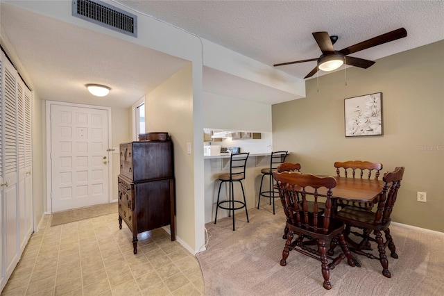 tiled dining area with ceiling fan and a textured ceiling