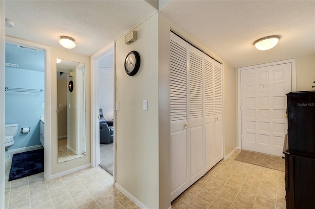 hall with a textured ceiling and light tile floors