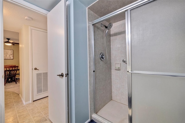 bathroom featuring a textured ceiling, ceiling fan, a shower with door, and tile flooring