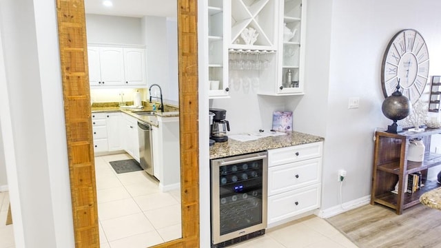 bar with light stone countertops, sink, white cabinets, beverage cooler, and dishwasher