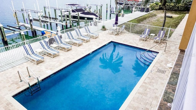 view of pool featuring a dock, a water view, and a patio