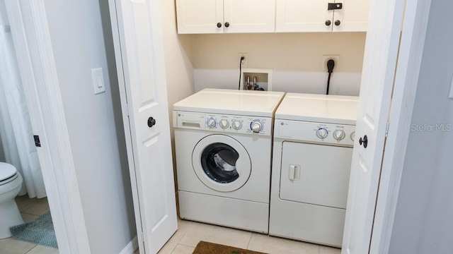 clothes washing area featuring cabinets, light tile flooring, independent washer and dryer, and electric dryer hookup