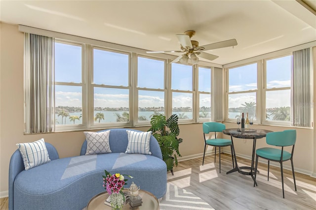 sunroom / solarium featuring ceiling fan and a water view