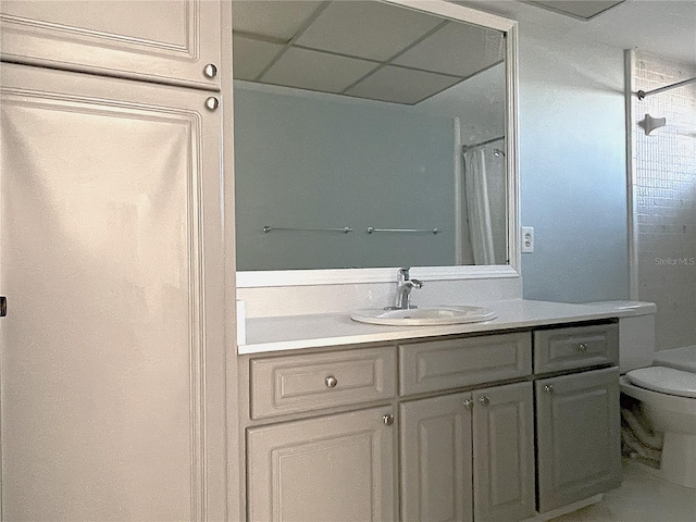 bathroom featuring a paneled ceiling, a shower with curtain, vanity, and toilet