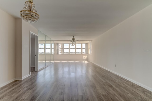 interior space featuring ceiling fan with notable chandelier, wood finished floors, and baseboards