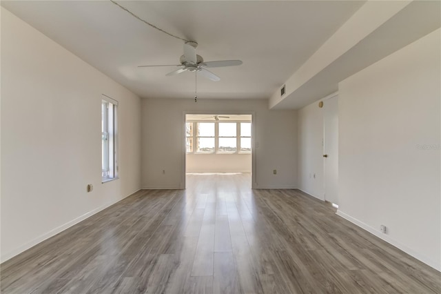 empty room featuring baseboards, wood finished floors, visible vents, and a ceiling fan